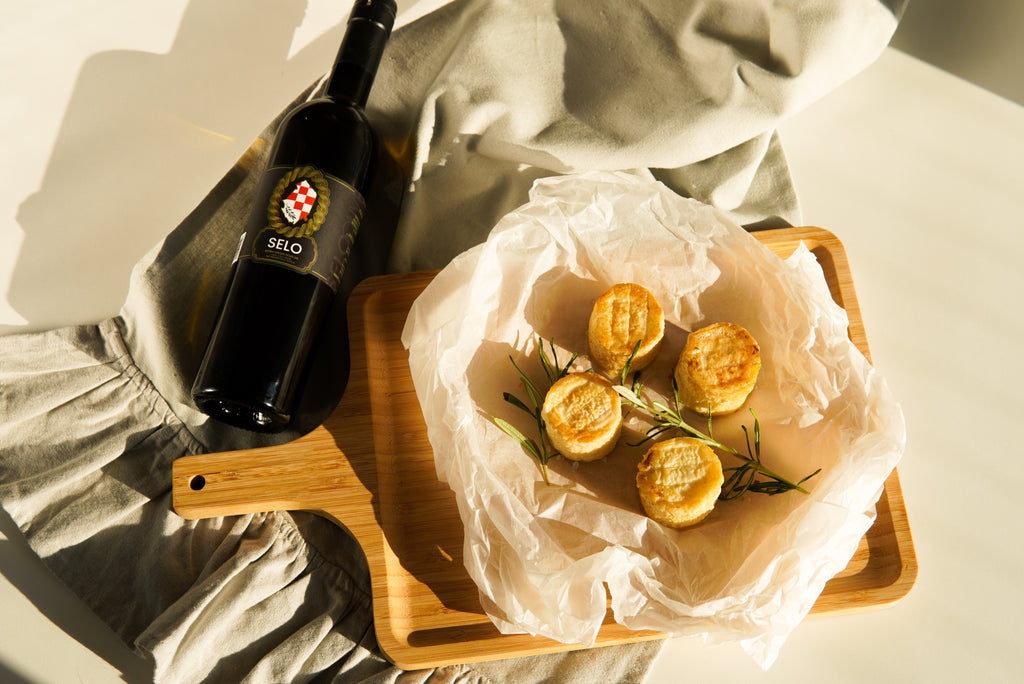 Crispy Fried Golden Goat Cheese Bites brushed with Croatian olive oil, arranged on a plate with a dipping sauce and garnished with fresh herbs, making for an irresistible appetizer.